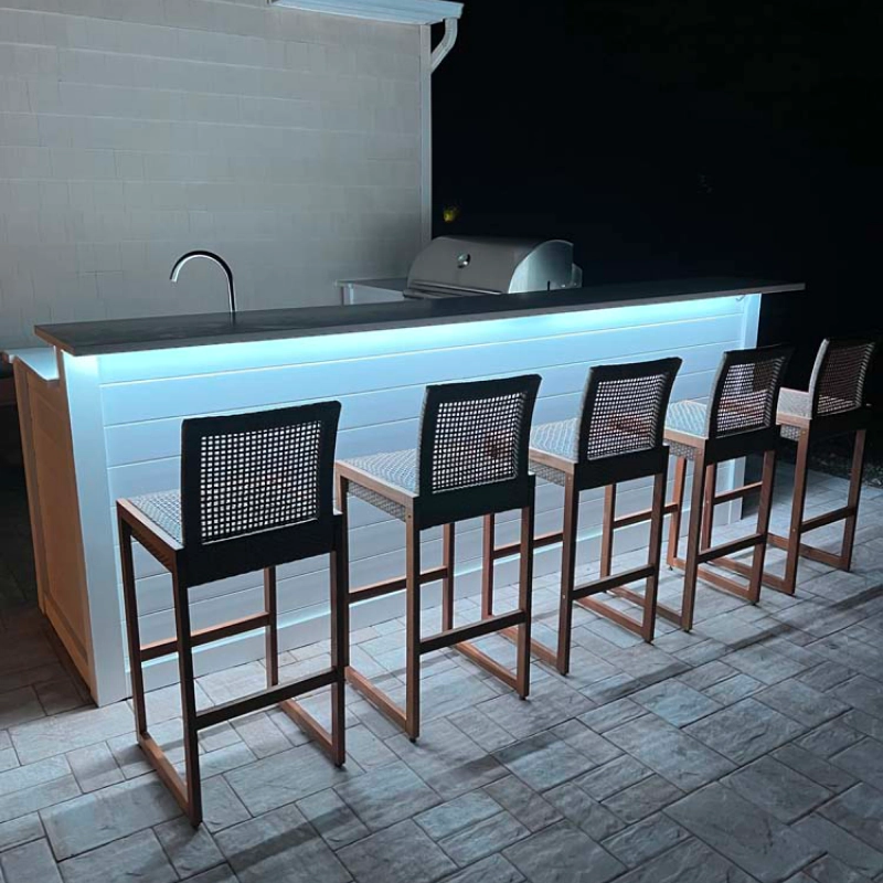 outdoor kitchen with a countertop with lights and wood chairs